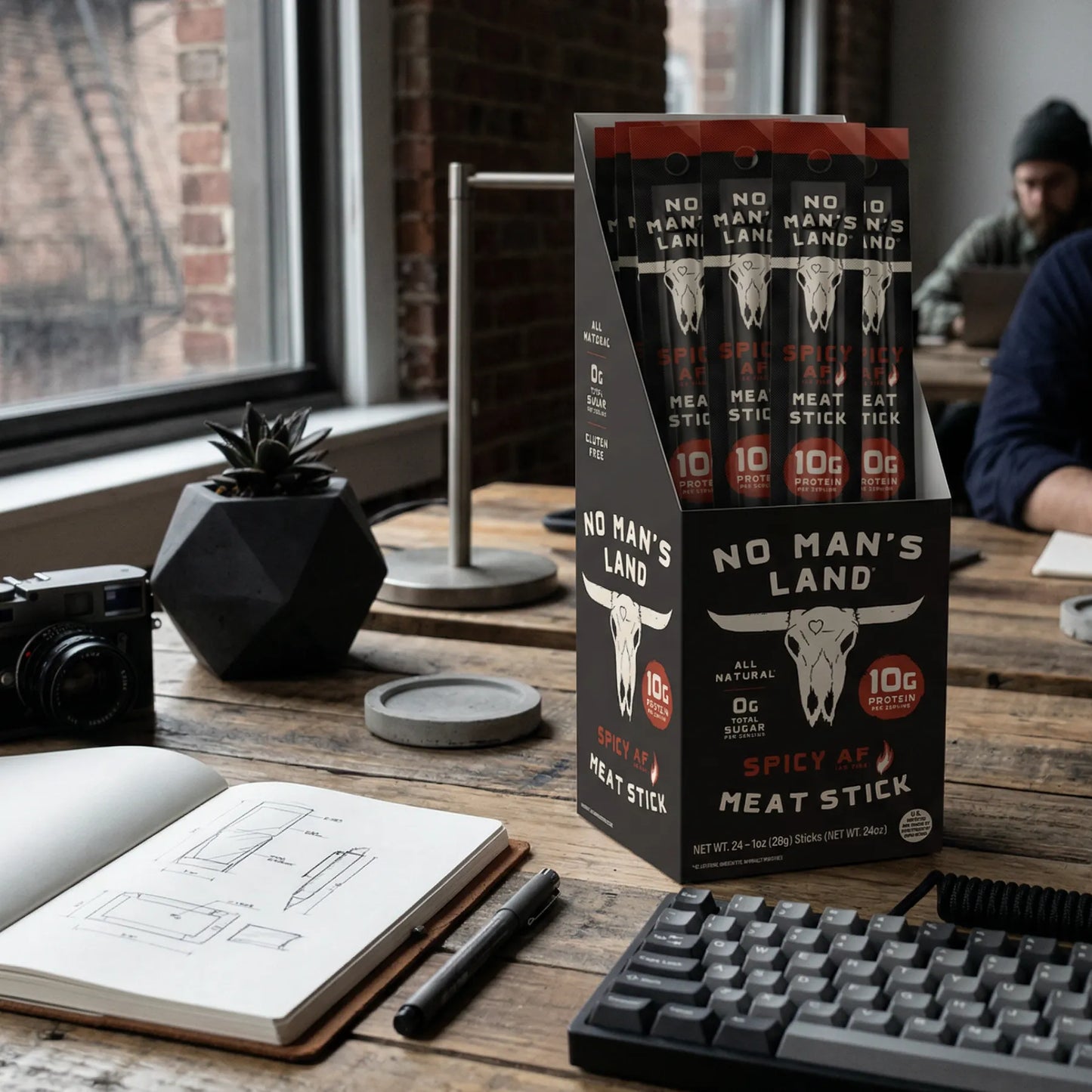 No Man's Land Spicy Meat Stick Spicy AF packaging on a desk with a person in the background