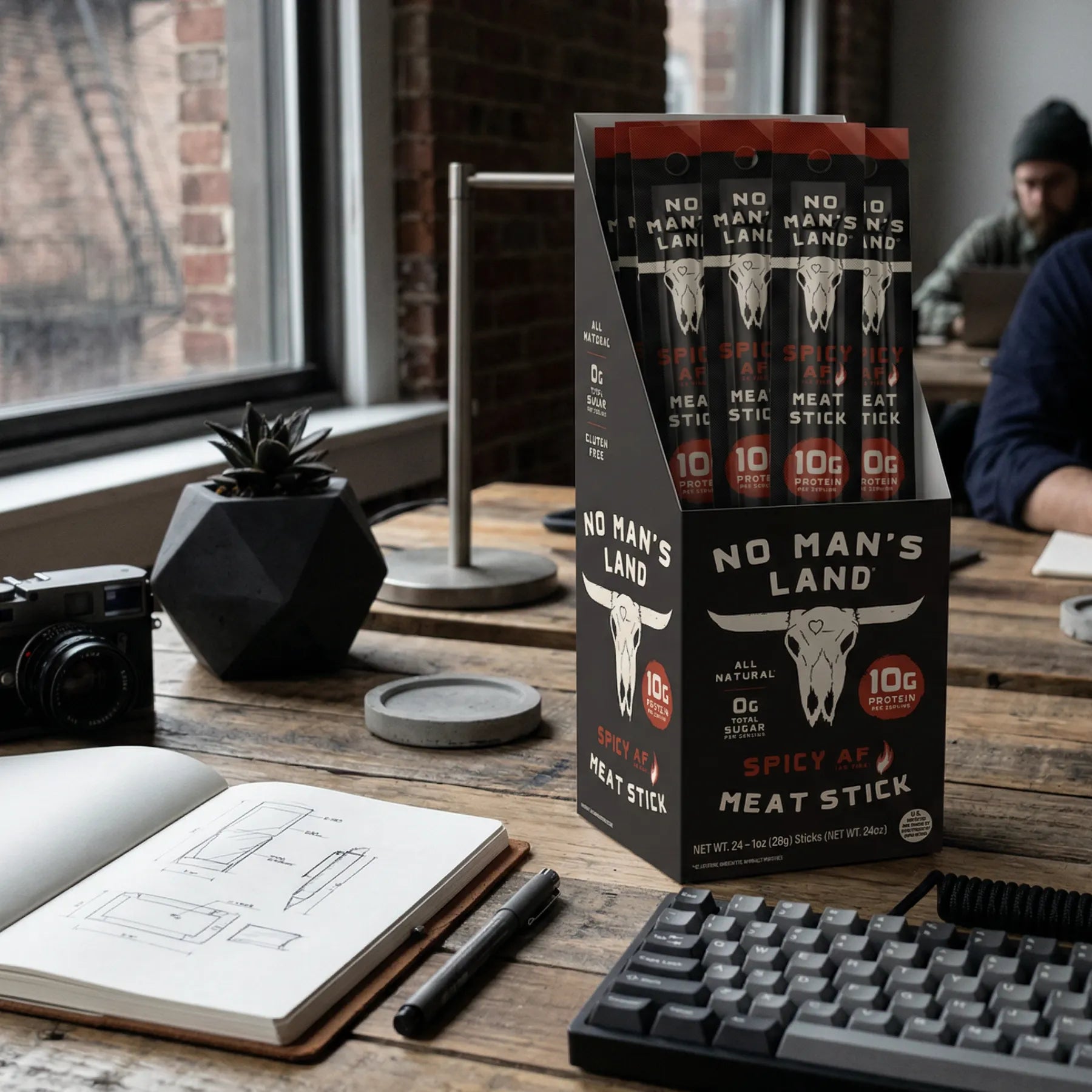 No Man's Land Spicy Meat Stick Spicy AF packaging on a desk with a person in the background