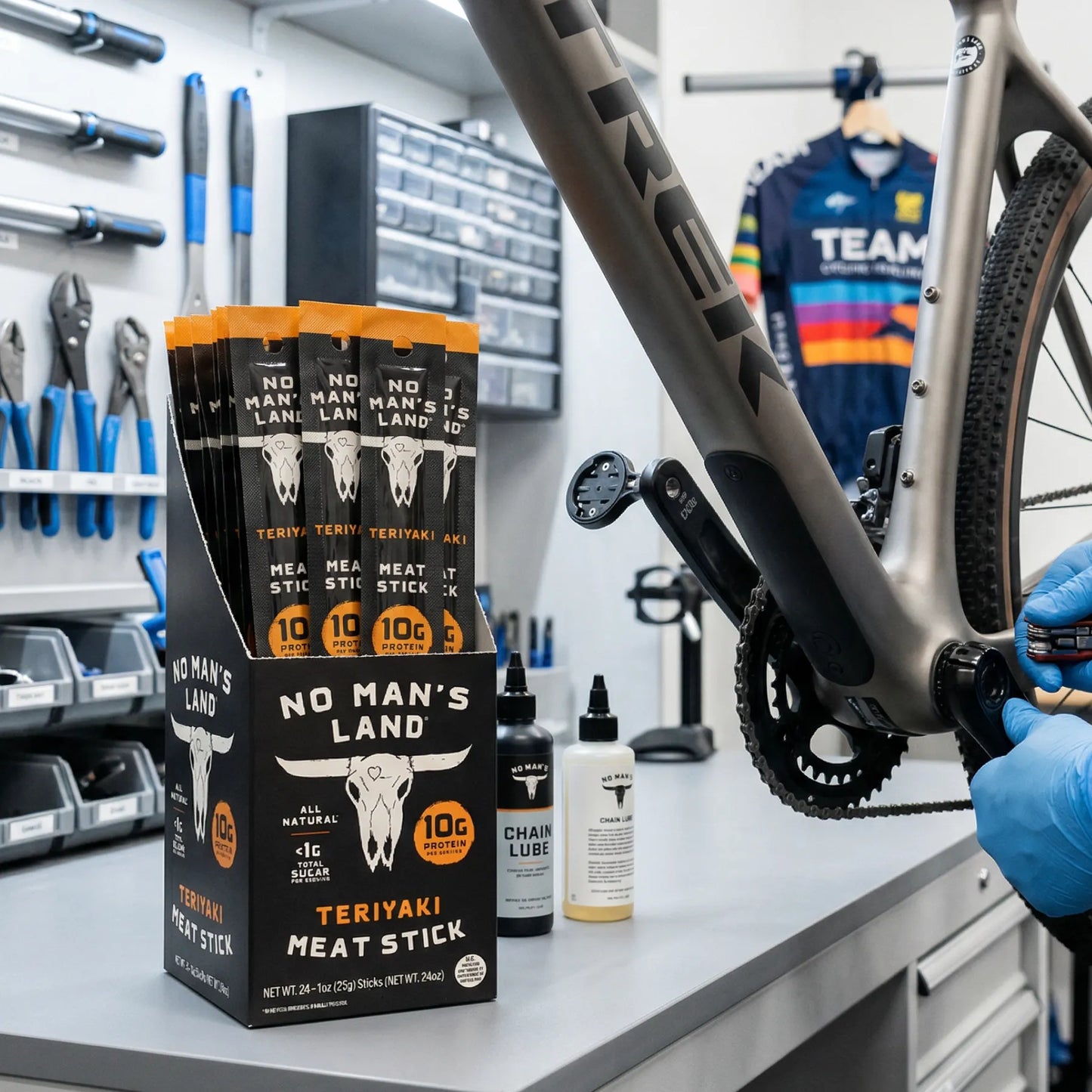 Bike repair setup with 'No Man's Land' Teriyaki meat sticks packaging on a workbench.
